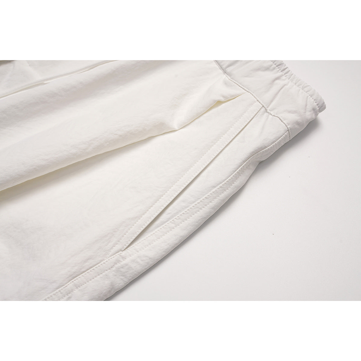 Close-up of the white pants' side seam and pocket opening.