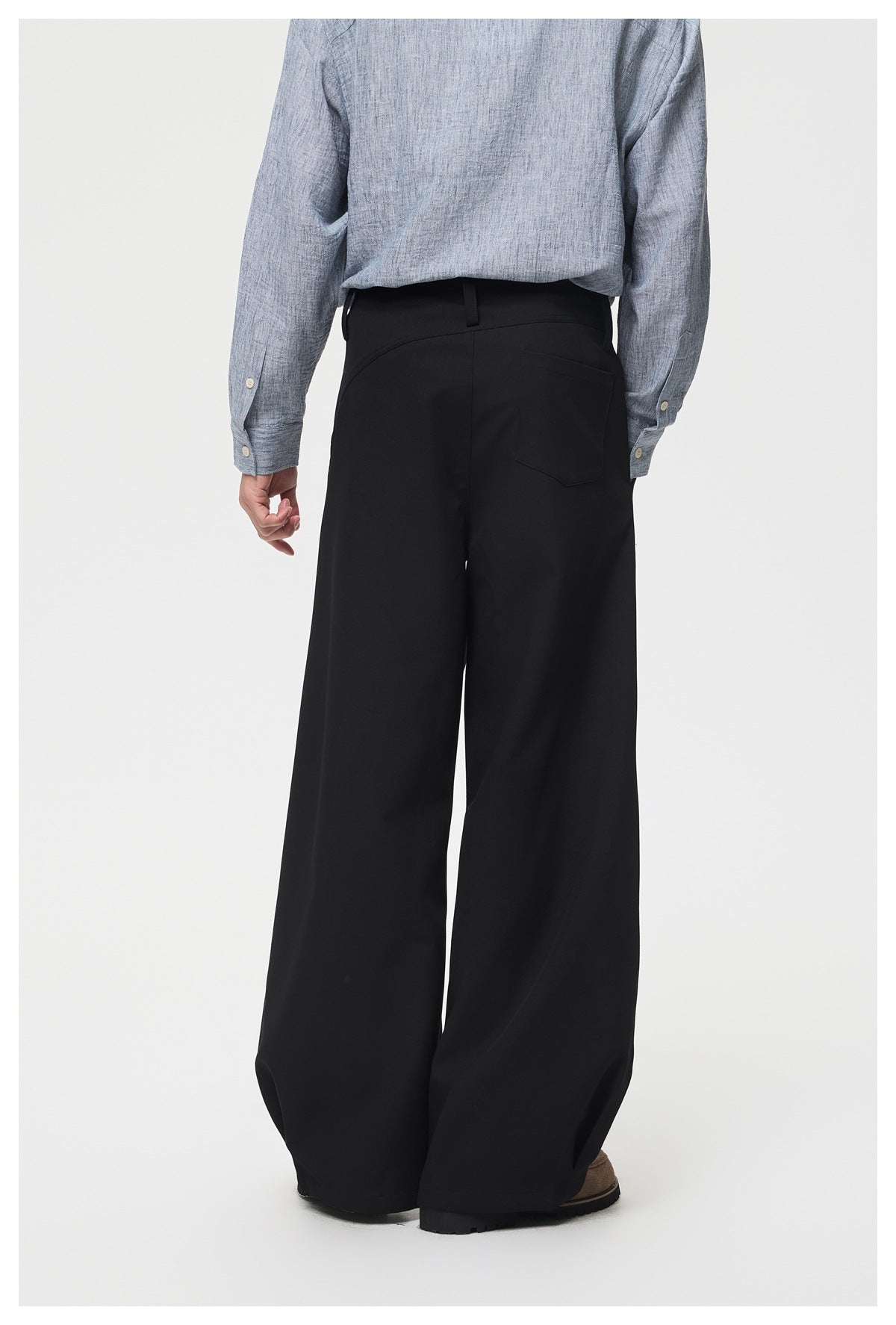 Back view of a model wearing black wide-leg trousers with a single rear pocket.