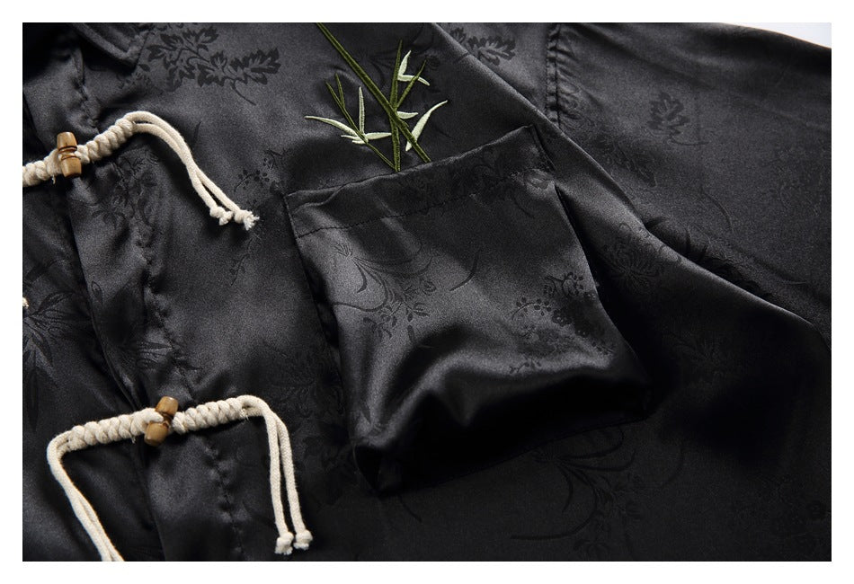 Close-up of a black floral-patterned shirt showing its patch pocket and cream rope closures.