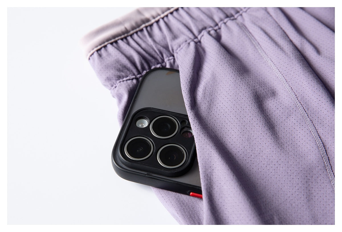 Close-up of a black phone tucked into the pocket of lavender perforated shorts.