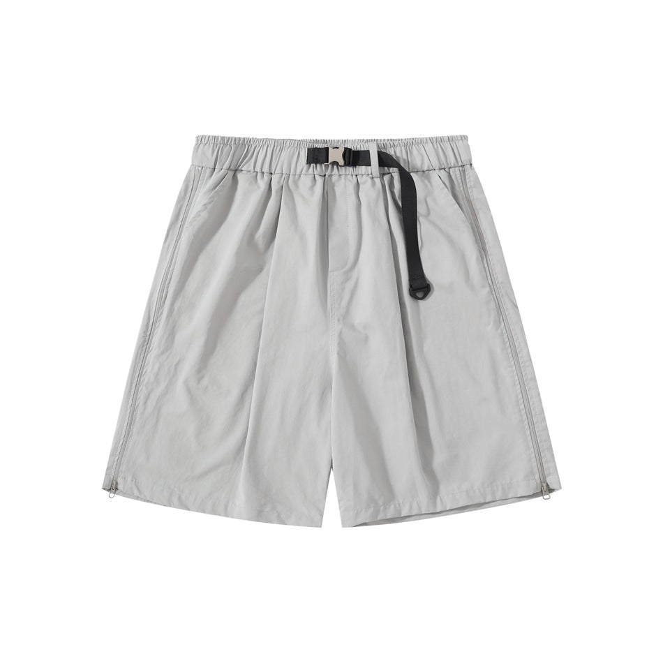 Light gray pleated knee-length shorts with elastic waist, black buckle strap belt and side hem zippers, front view