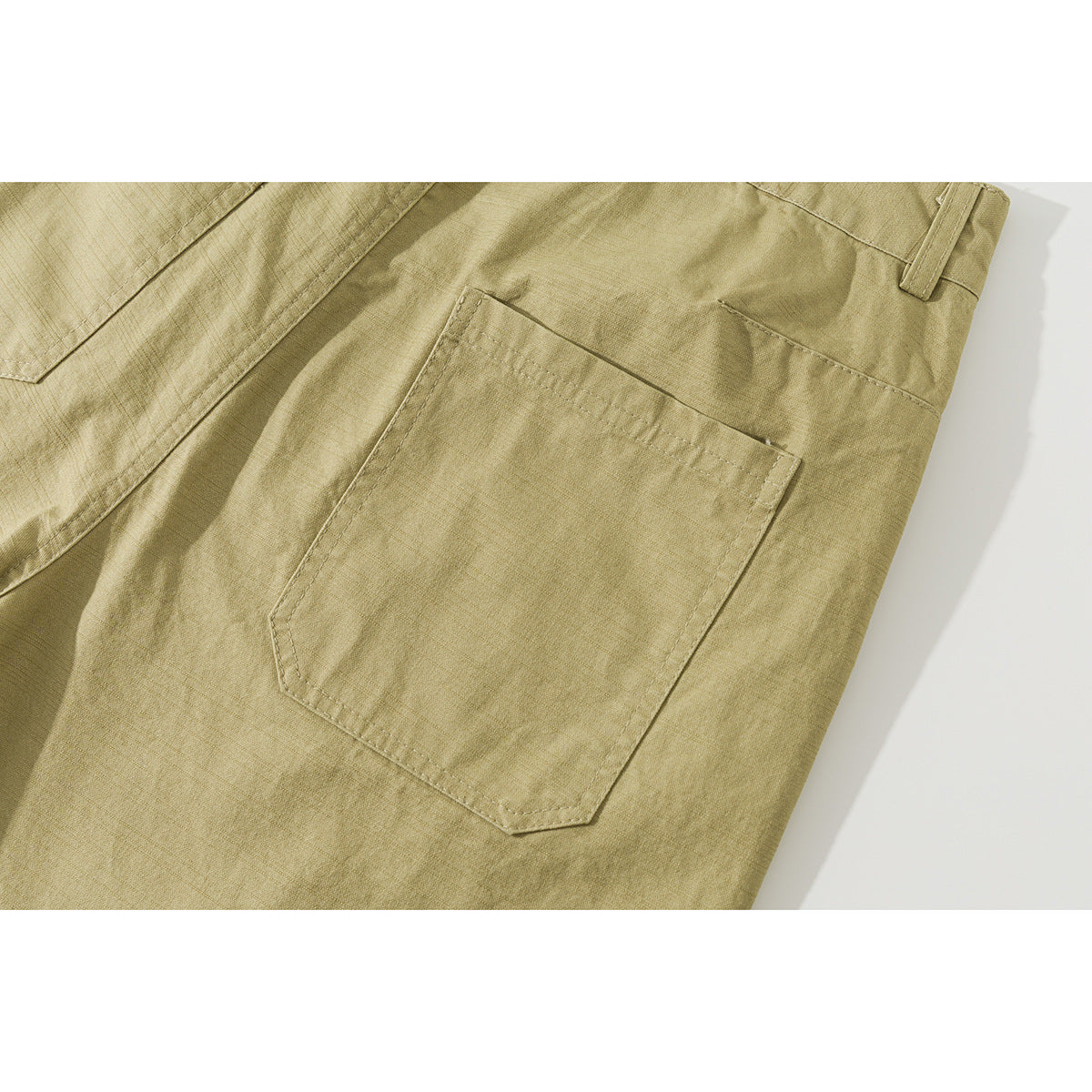 Close-up of khaki shorts showing a large rear pocket, stitching and waistband edge.