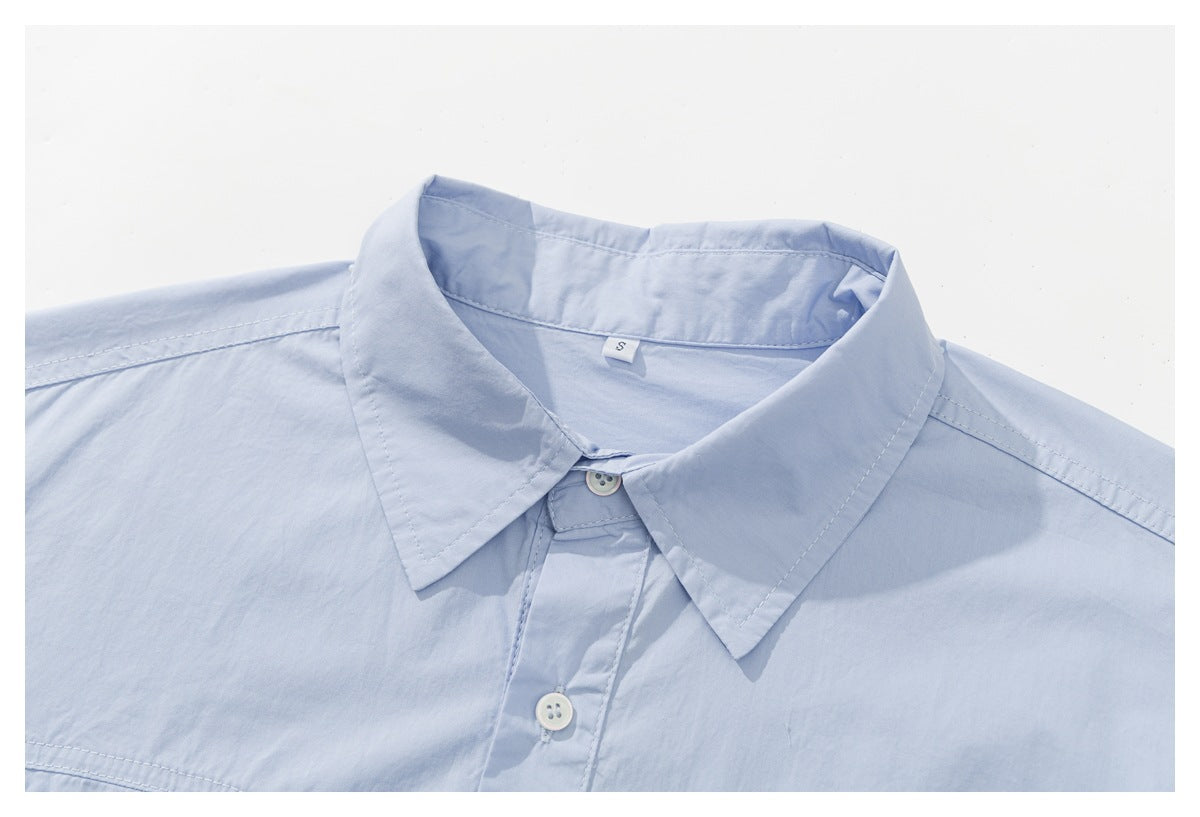 Close-up of a pale blue button-up shirt showing its pointed collar, placket and white buttons.