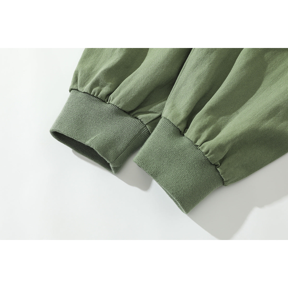 Close-up of gathered sage-green jacket sleeves ending in wide ribbed cuffs.