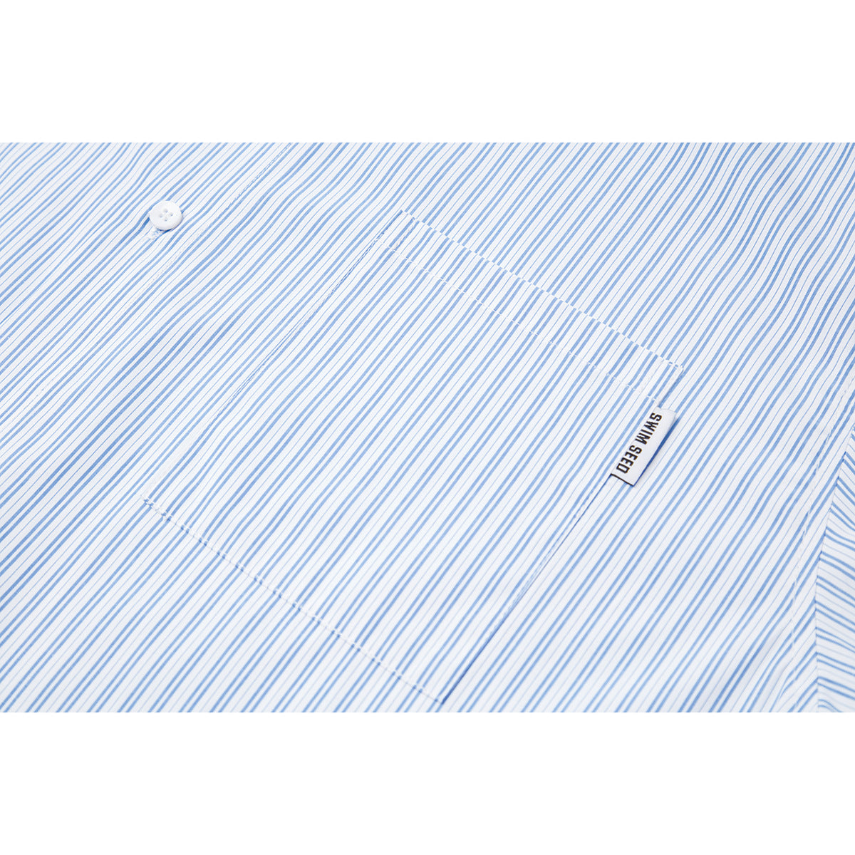 Close-up of a white-and-blue striped shirt showing its chest pocket, button, and small SWIM SEED tag.