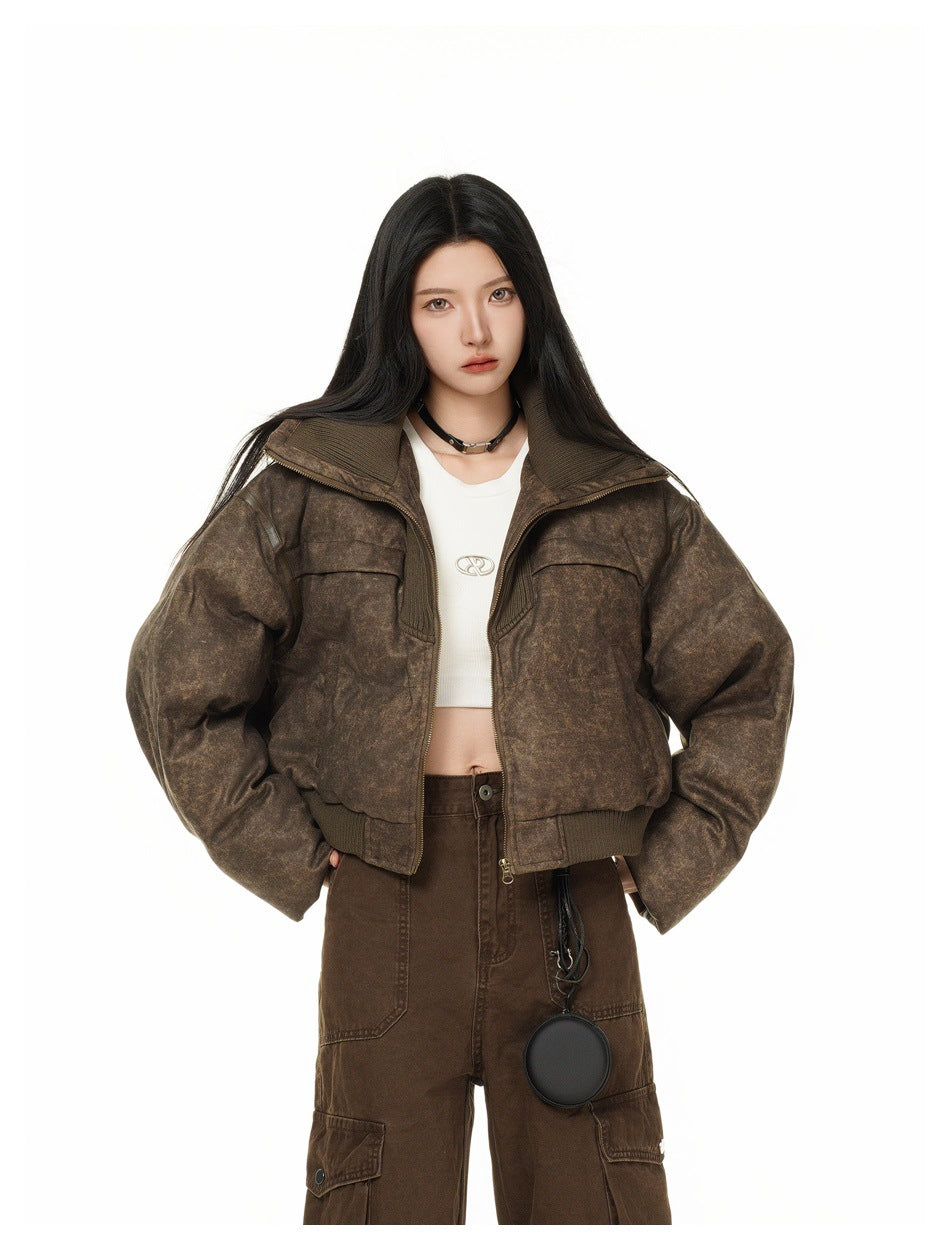 Model wearing a mottled brown cropped zip jacket over a white crop top with dark brown cargo pants, shown from the front.
