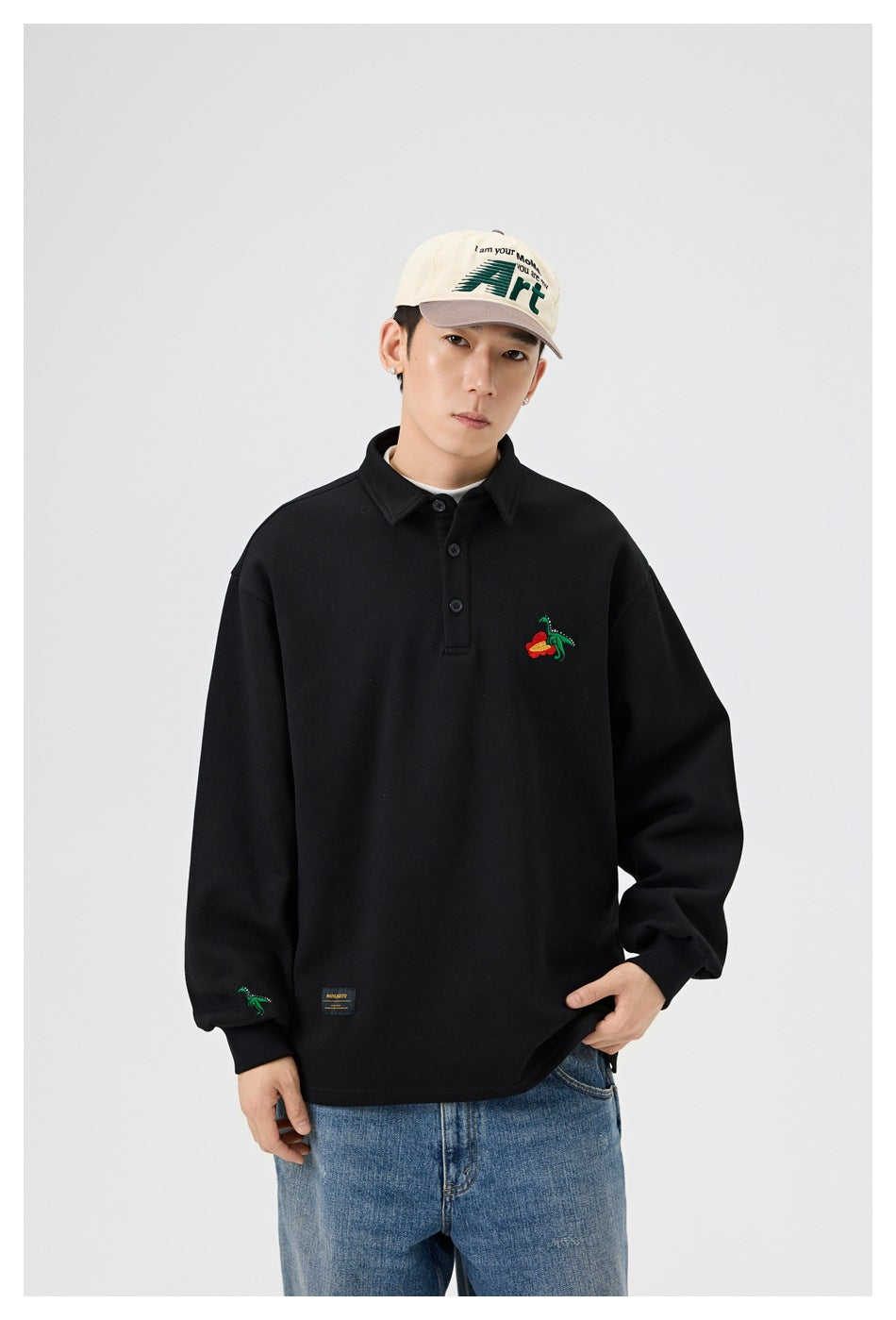 Closer front view of a model in a black long-sleeve collared pullover with colorful chest and sleeve embroidery.