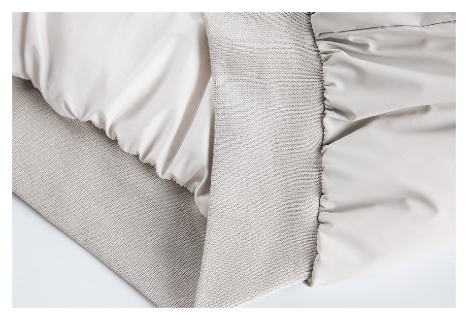 Close-up of pale gray gathered fabric beside a wide ribbed knit band.