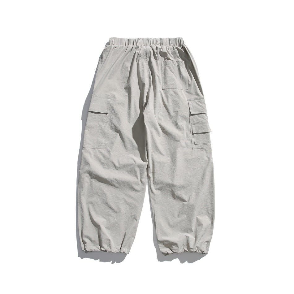 Back view of light gray cargo joggers with an elastic waist, rear patch pocket, side cargo pockets, and gathered cuffs.