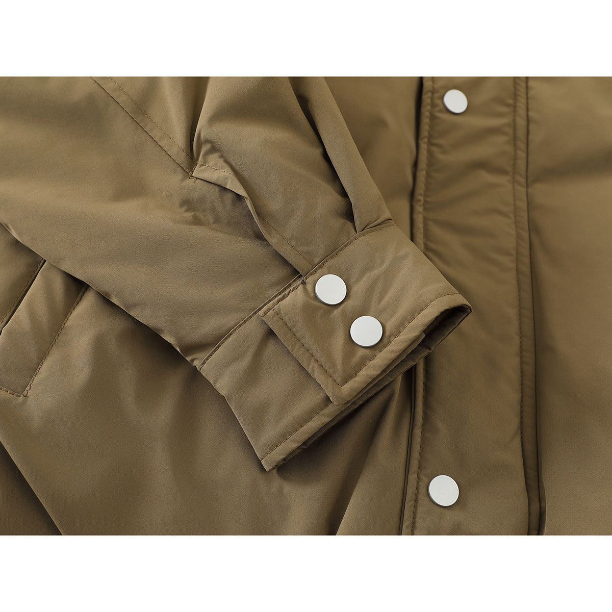 Close-up of a tan jacket sleeve and cuff with two silver snaps, alongside the front snap placket.