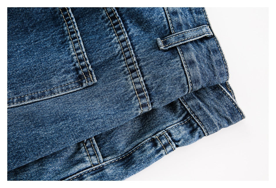 Close-up of folded blue jeans showing the waistband, belt loop, pocket edges and contrast stitching.