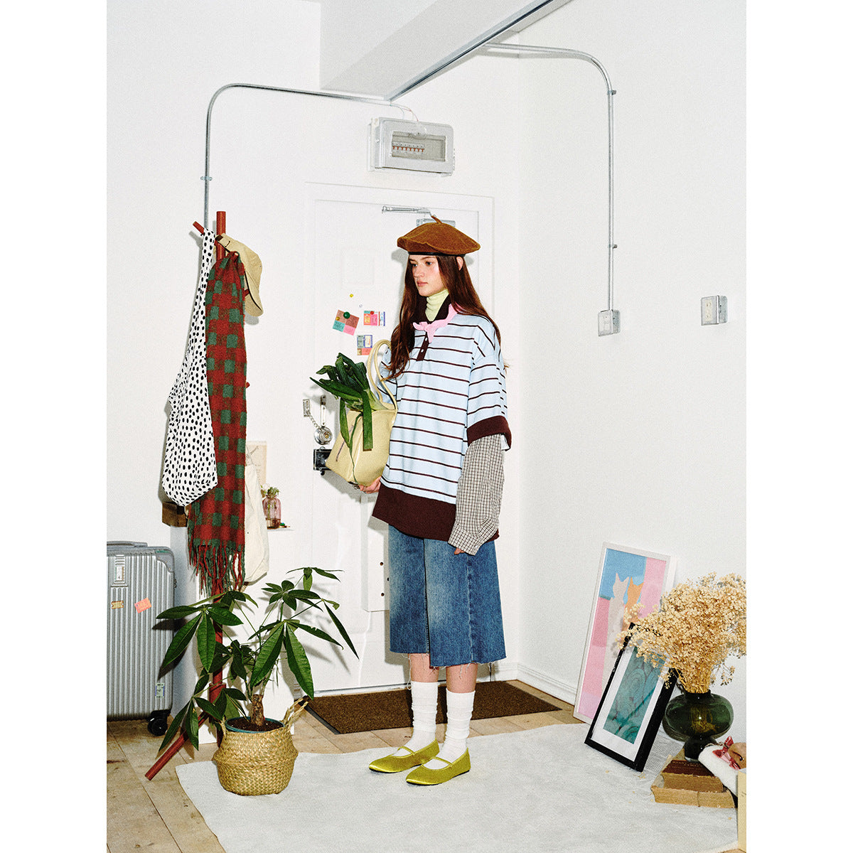 Model wearing a light blue striped polo-style top with brown trim and plaid layered sleeves, paired with denim culottes.
