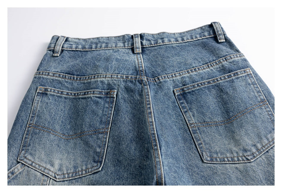 Back view of blue washed jeans laid flat, showing two rear pockets, belt loops, and contrast stitching.