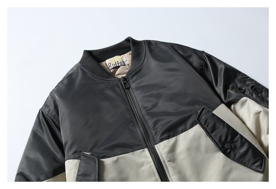 Close view of a black and light beige color-block bomber jacket front with a zip closure and snap pocket.