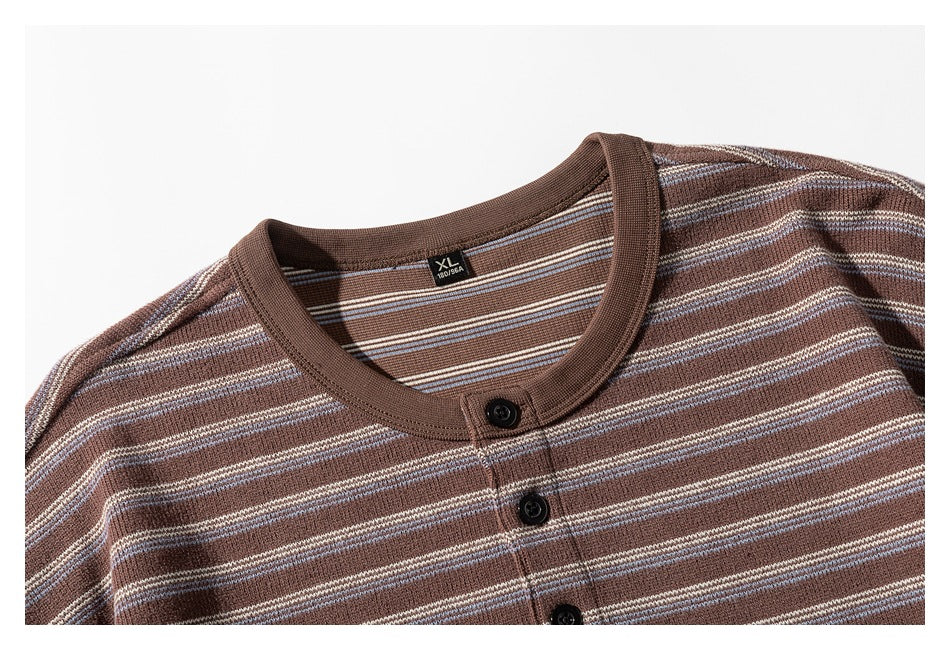 Close-up of a brown striped knit shirt's crew neckline and three-button placket.