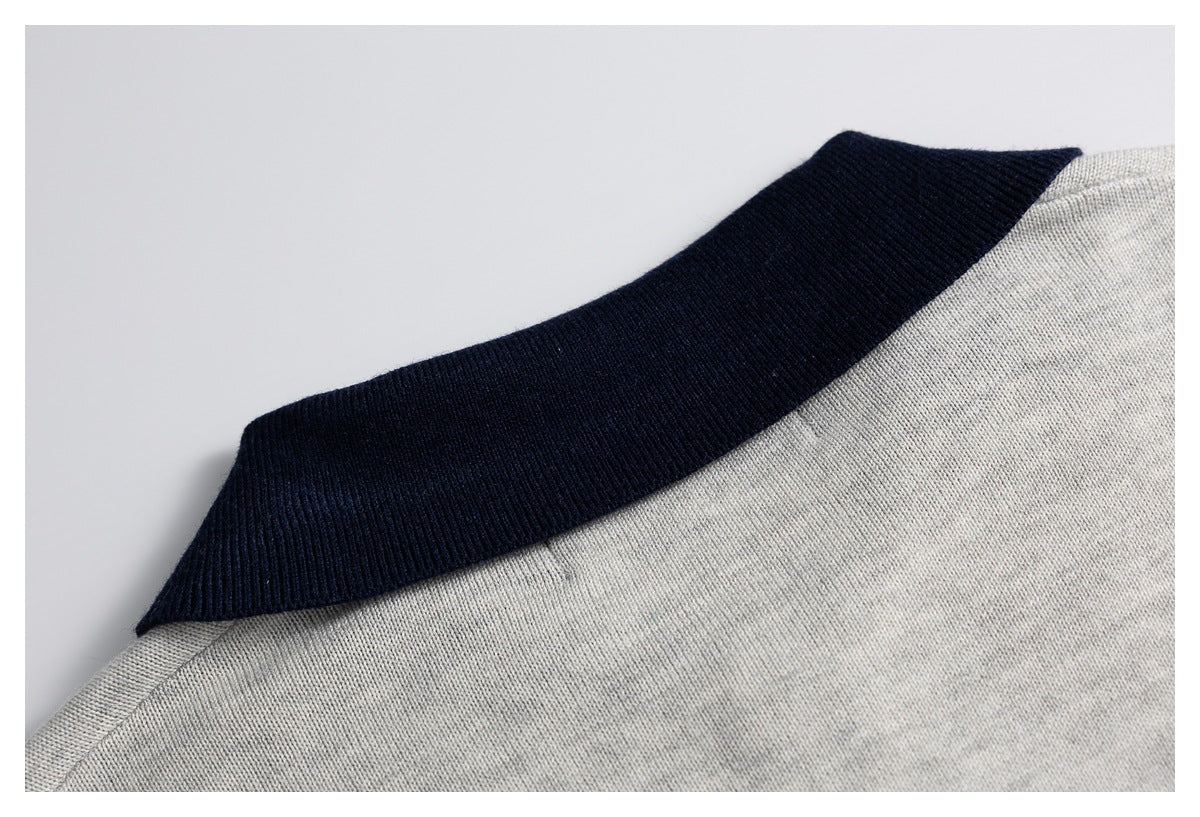 Close-up of a light gray knit sweater with a dark navy ribbed collar.