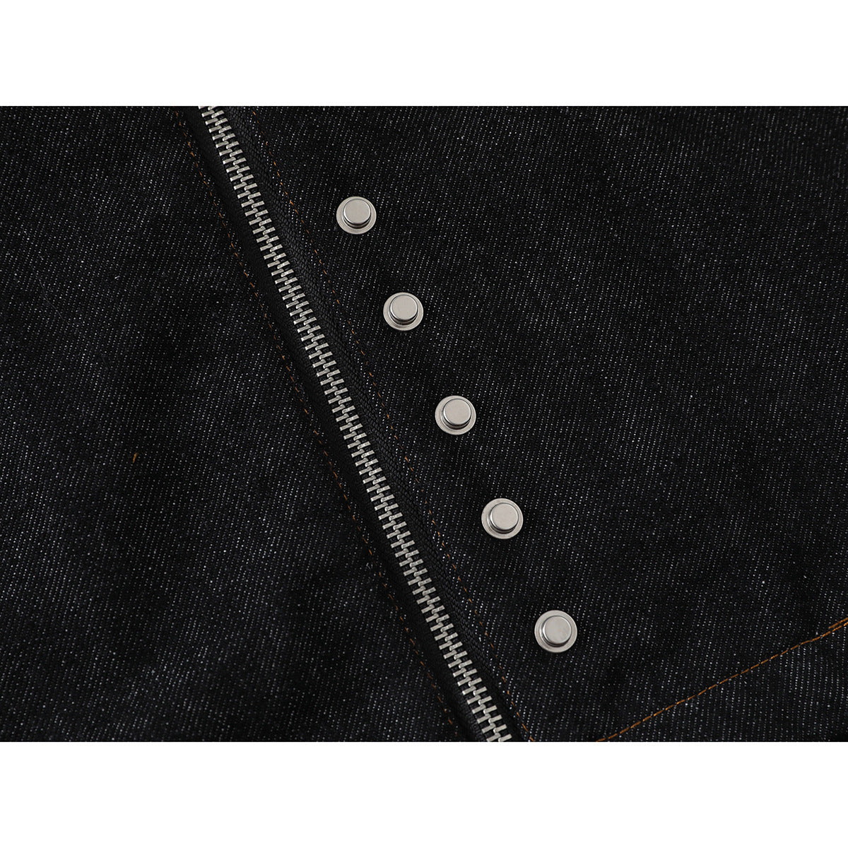 Close-up of a black denim jacket’s silver front zipper and a row of metal snap fasteners.