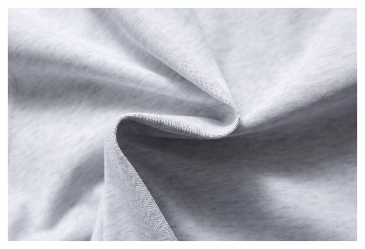Close-up of light gray knit fabric draped into soft folds, showing its surface texture.