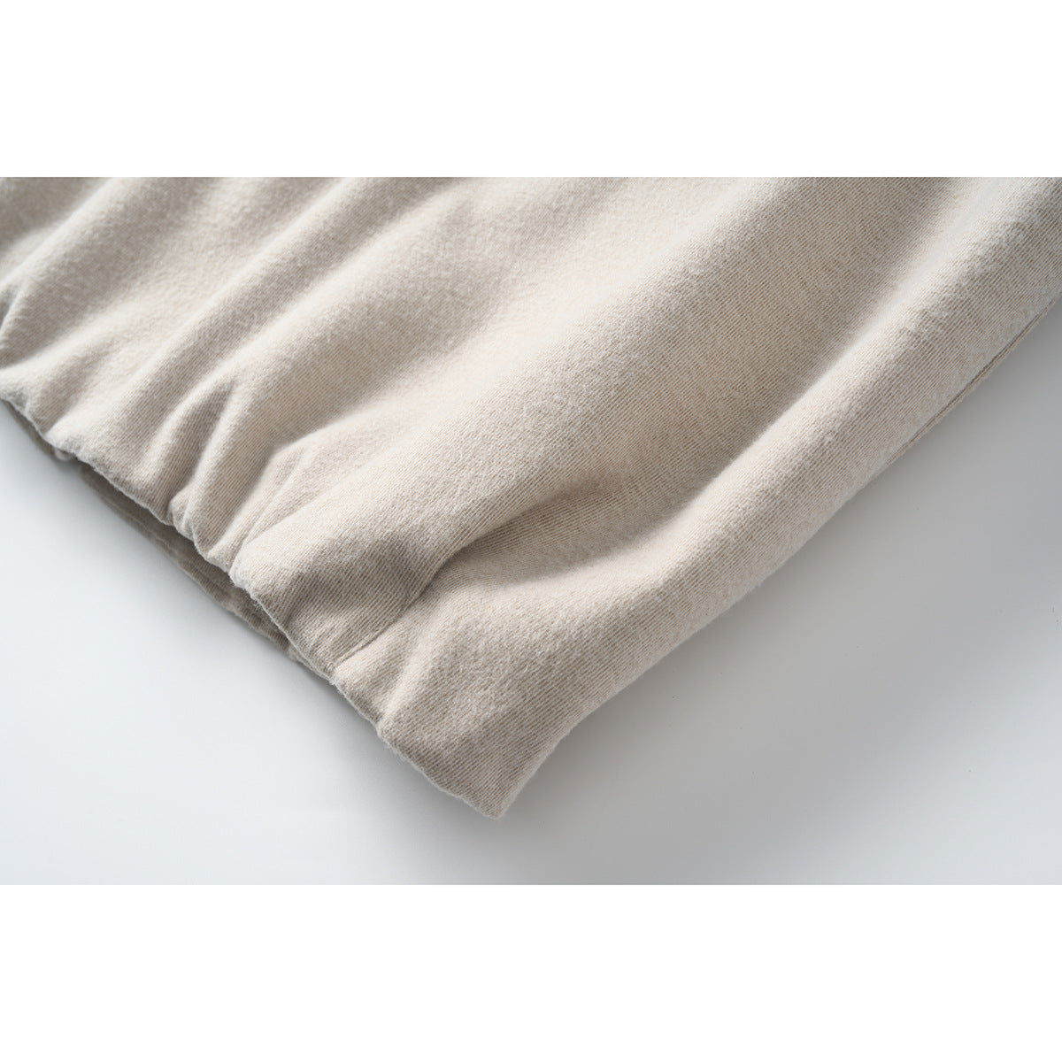Close-up of a gathered cuff and sleeve edge on the light beige jacket.