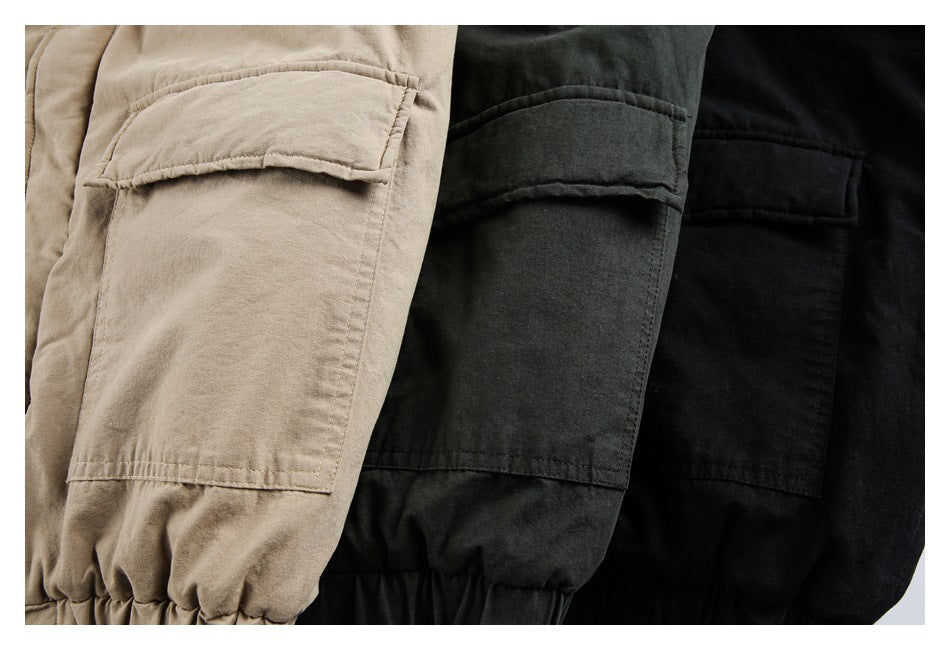 Close-up of tan, charcoal, and black hooded jackets showing flap pockets and gathered cuffs.