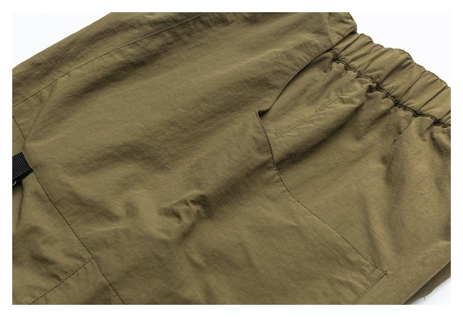 Close-up of olive-khaki pants showing the elastic waistband, large pocket, and black tab.