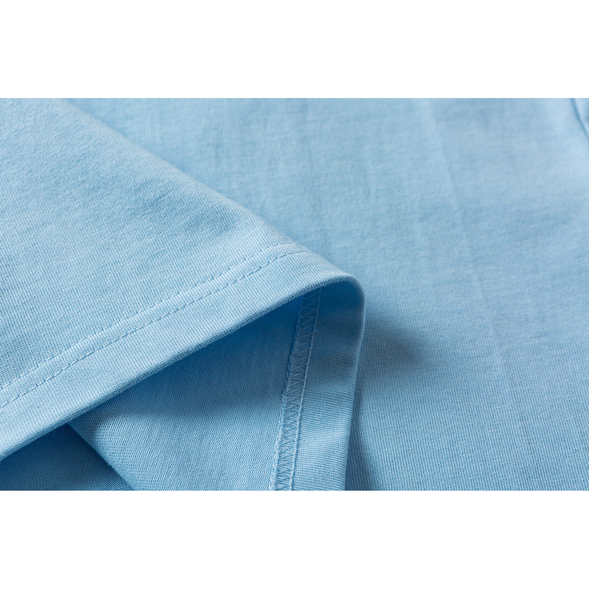 Close-up of the light blue T-shirt fabric and stitched sleeve hem.