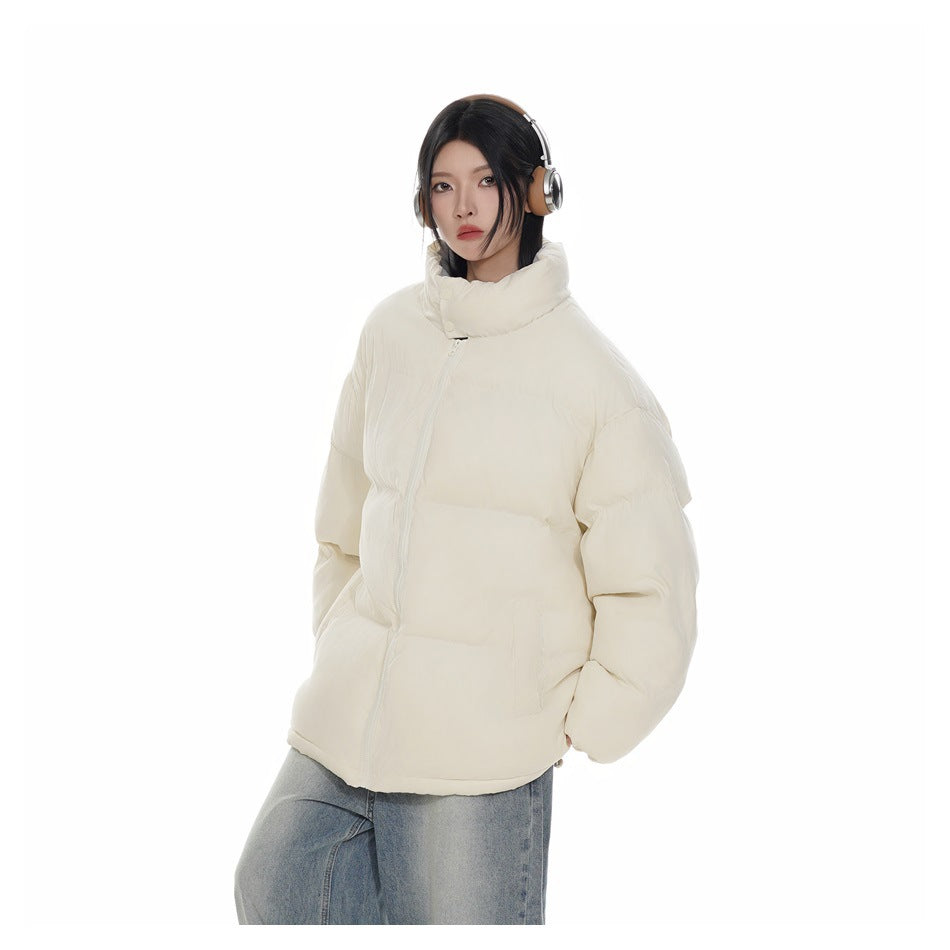 Model wearing a beige puffer jacket zipped up with a stand collar, headphones and light-wash jeans, three-quarter view