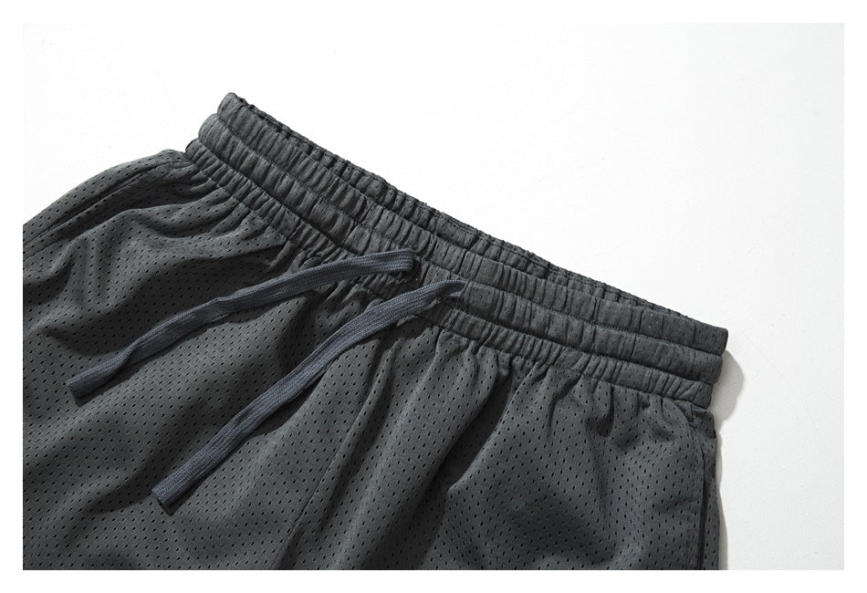 Close-up of charcoal perforated shorts with an elastic waistband and matching drawstrings.