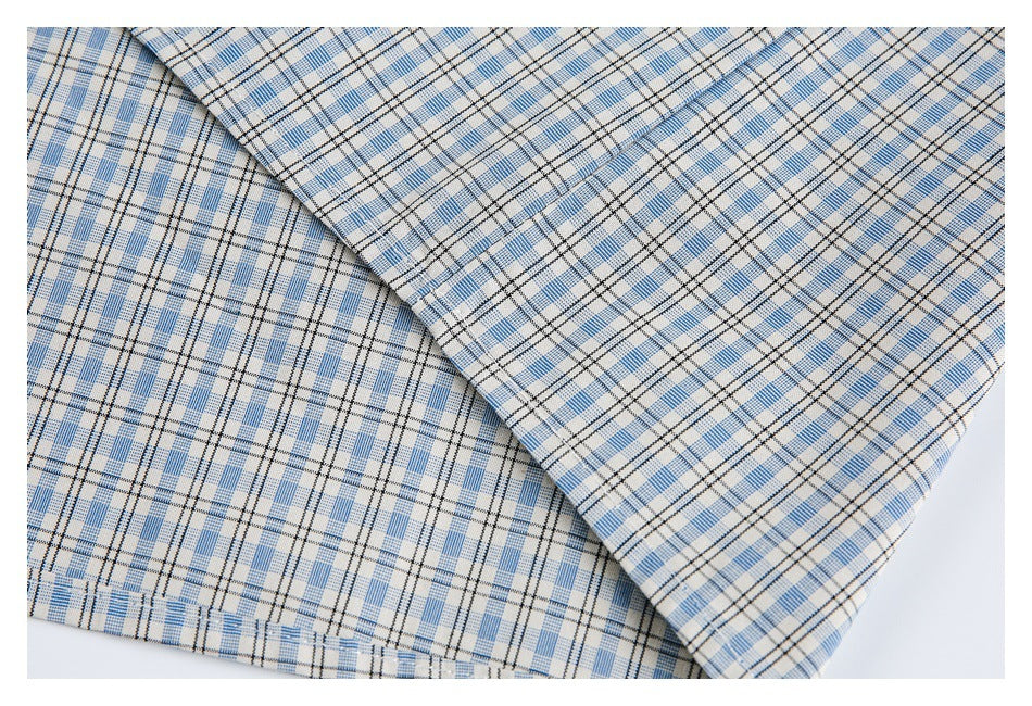 Close-up of folded fabric with a light blue, beige, and black plaid pattern.