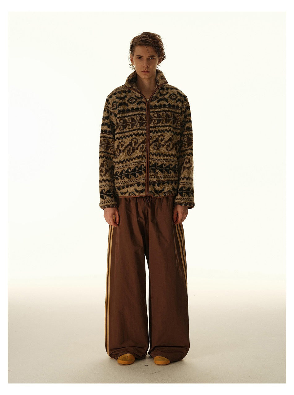 Model wearing a brown-and-black patterned zip-front jacket with a raised collar and loose brown trousers.