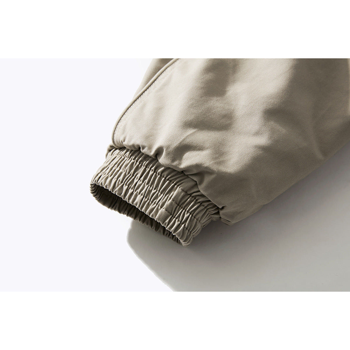 Close-up of a light beige jacket sleeve ending in a gathered elastic cuff.