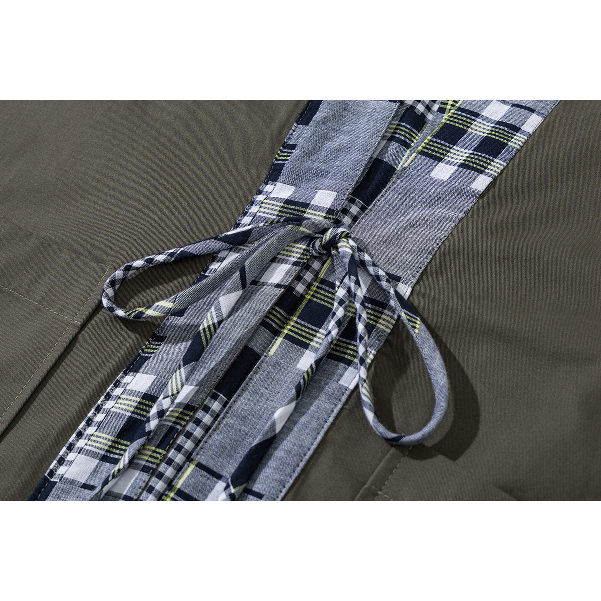 Close-up of an olive jacket's plaid front ties knotted at the waist.
