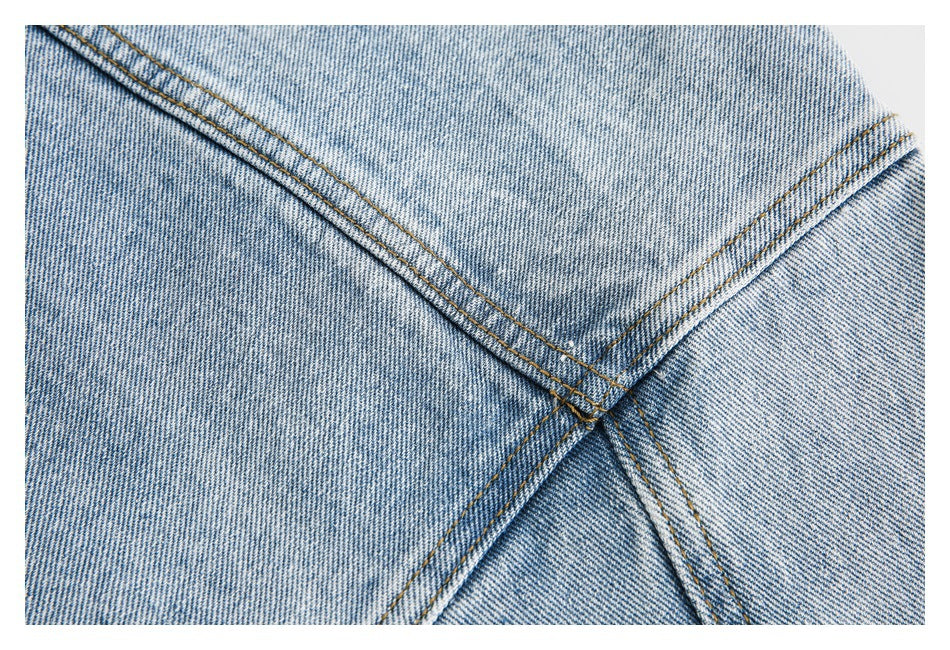 Close-up of intersecting tan-stitched seams on light-wash denim.