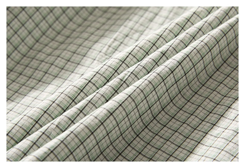 Close-up showing the fine green and dark plaid pattern across folded shirt fabric.