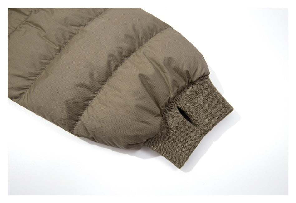 Close-up of a taupe quilted sleeve ending in a dark rib-knit cuff with a thumb opening.