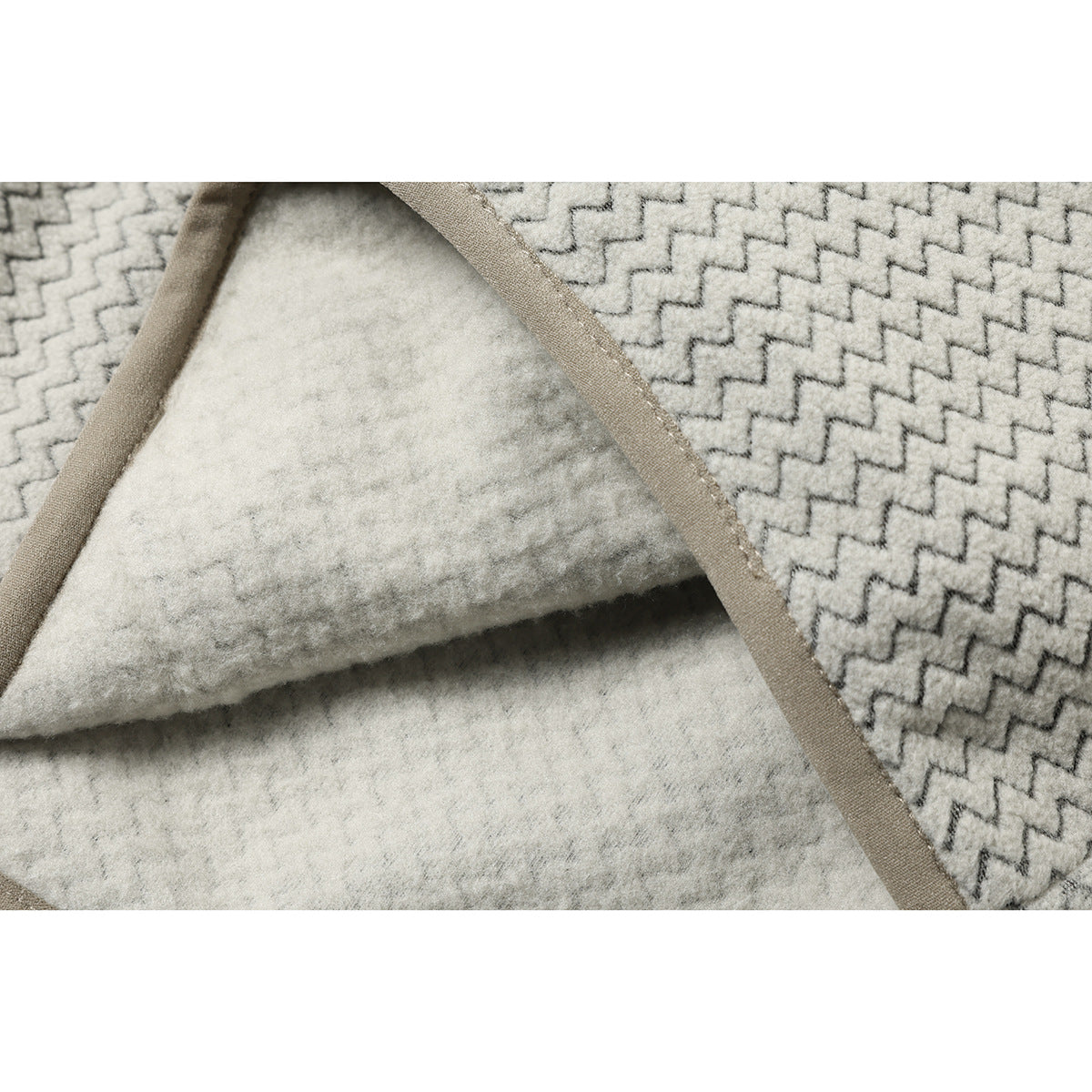 Close-up of the garment's cream fuzzy inner surface, bound seam, and gray zigzag-patterned outer fabric.