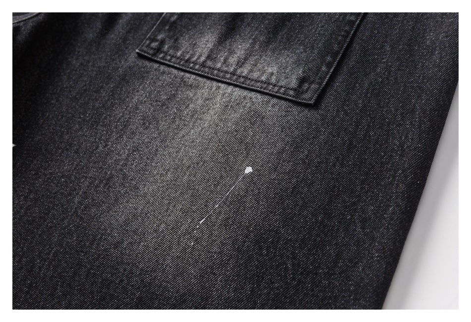 Close-up of a black denim trouser pocket and fabric with a small white paint-like spot.