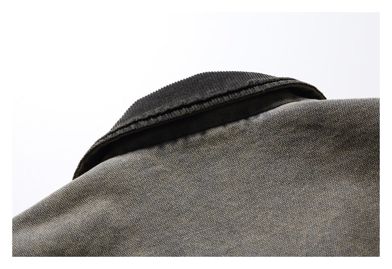 Close-up of a dark ribbed collar against mottled gray-olive garment fabric.