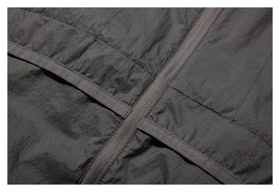 Close-up of the charcoal jacket's back zipper and curved horizontal seam.