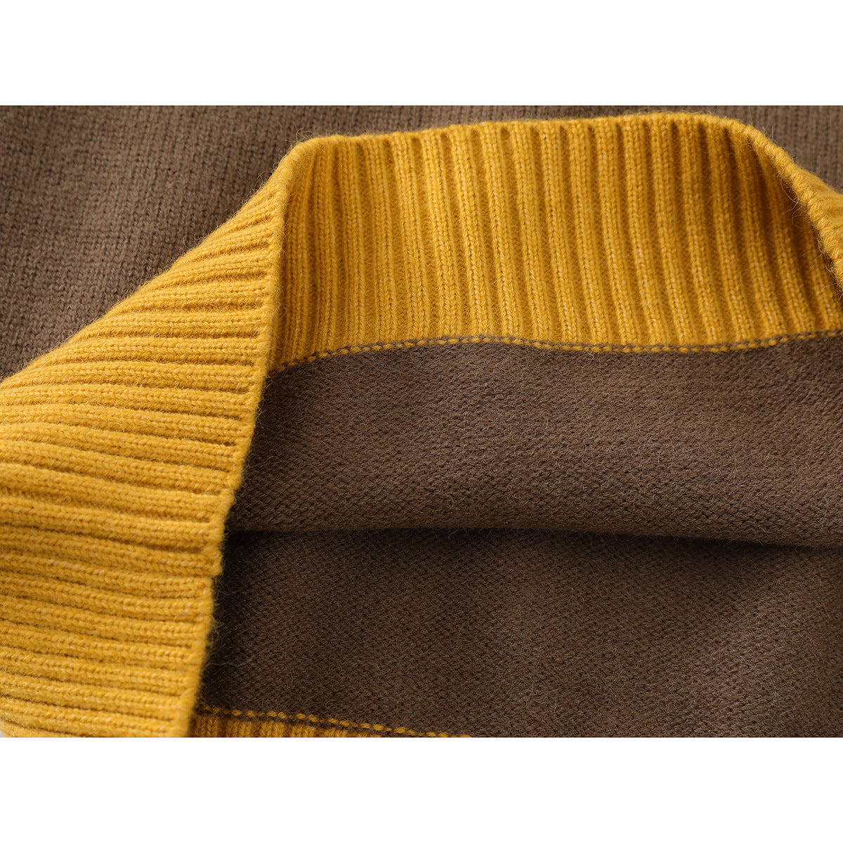 Close-up of mustard yellow ribbed sweater trim against brown knit fabric, showing the seam and texture.