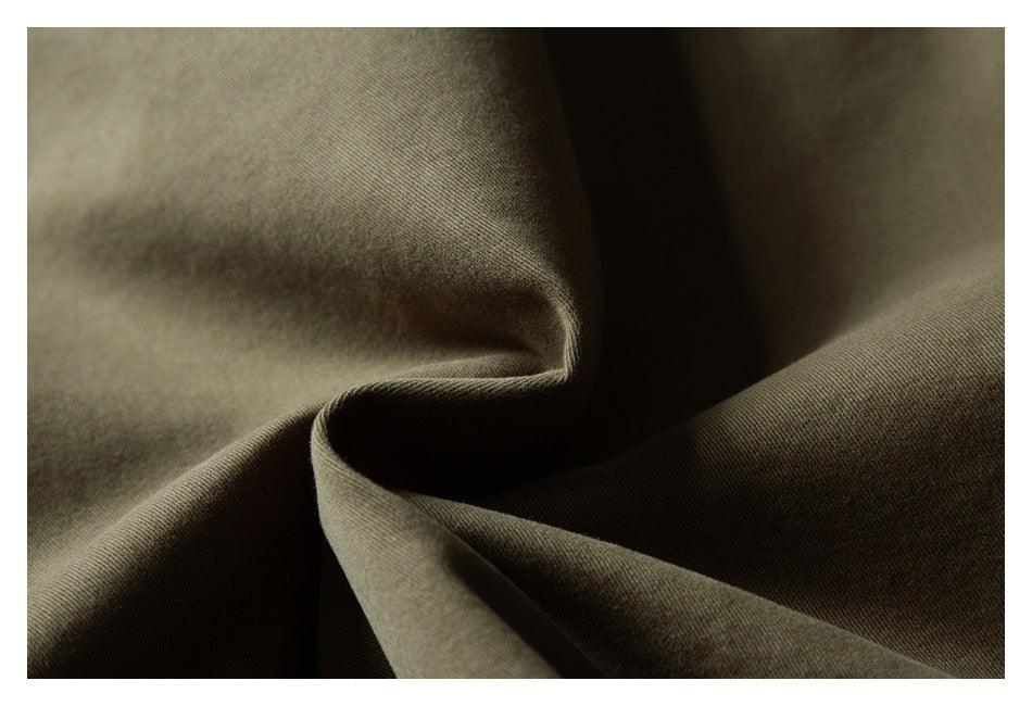 Close-up of olive-brown fabric folded into soft ridges, showing its fine woven texture.