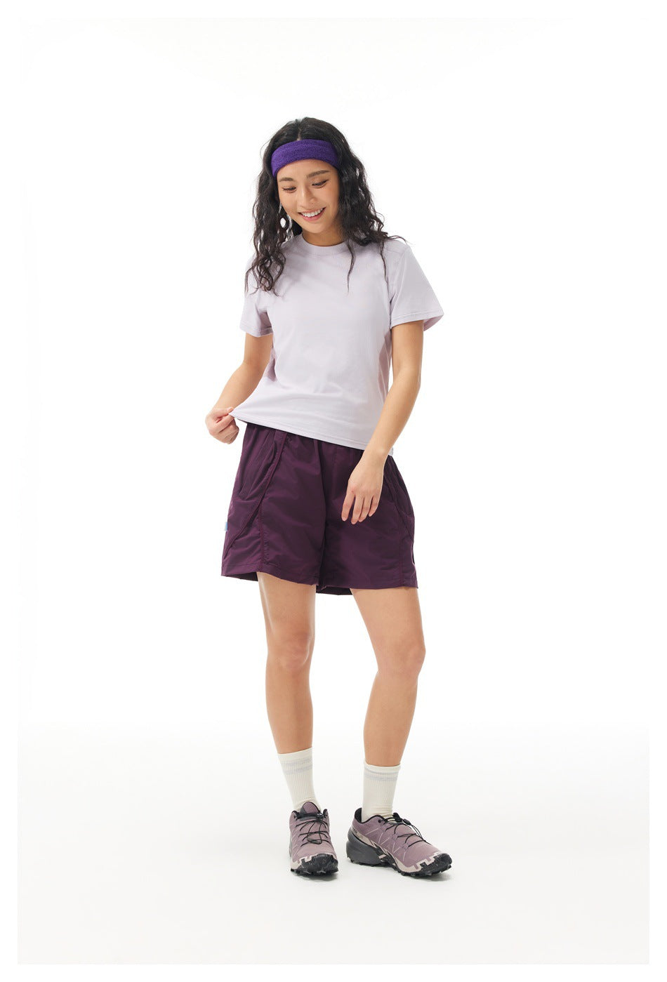 Woman wearing a light lavender short-sleeve shirt and plum shorts, shown from the front.