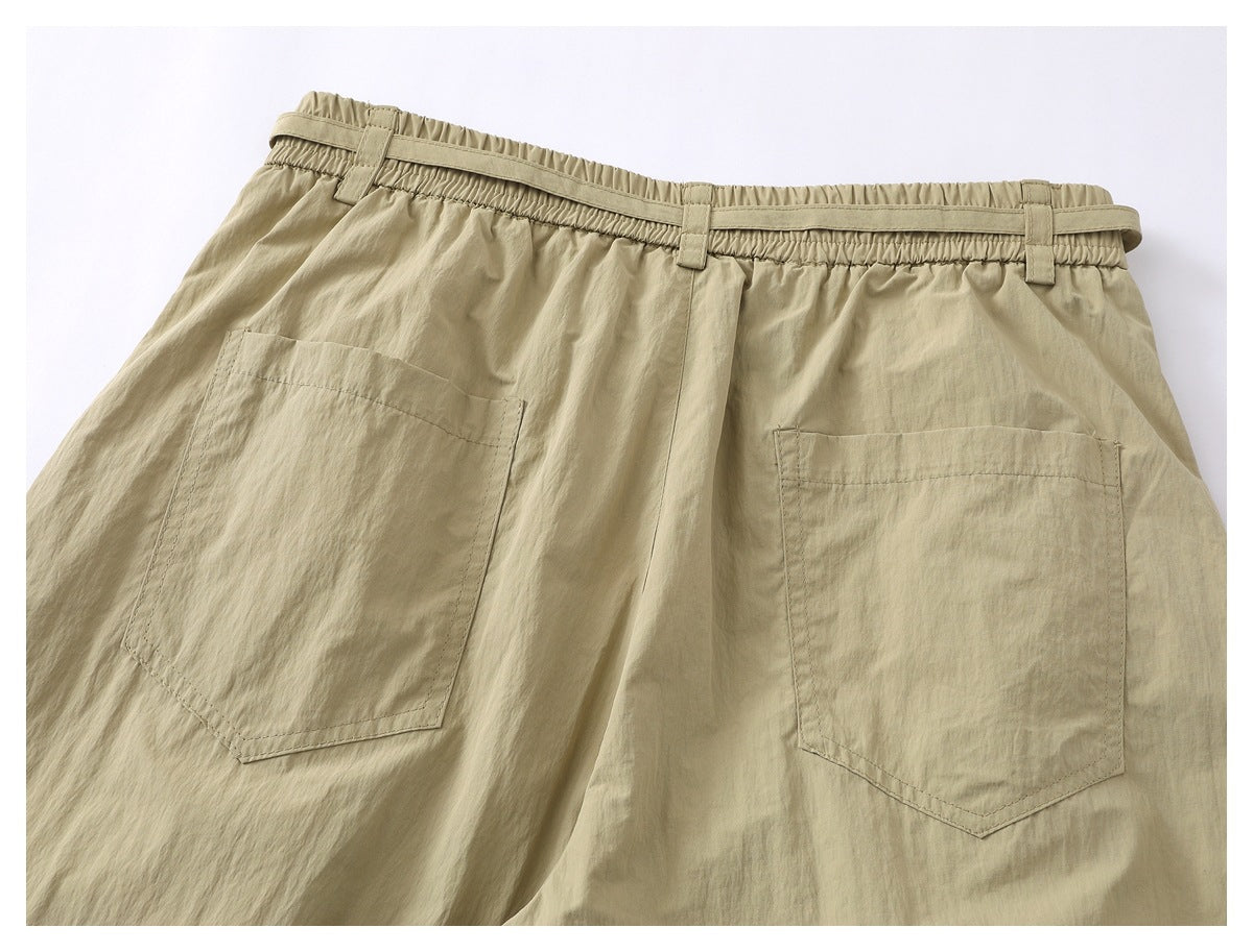 Close rear view of light khaki pants with an elastic waistband, belt loops, and two large patch pockets.