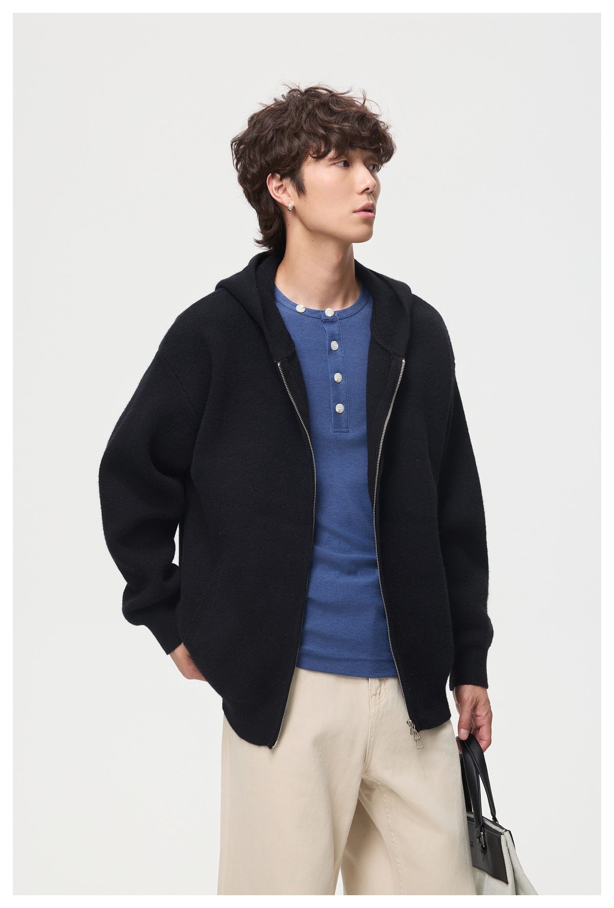 Model wearing a black zip-front hooded cardigan over a blue button-neck shirt.