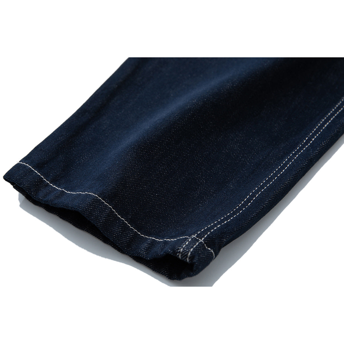 Close-up of a dark indigo jeans leg hem with double-row contrast stitching.