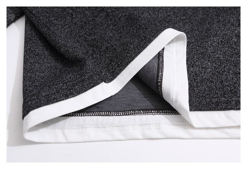Close-up of the charcoal marled garment's white-trimmed hem and visible inside stitching.