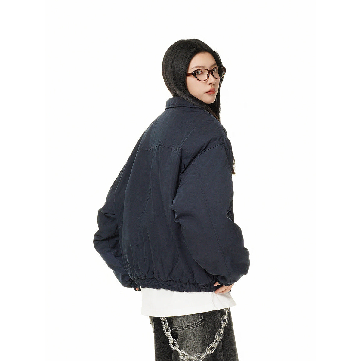 Model wearing an oversized navy jacket, shown mostly from the back with a white shirt and dark jeans.