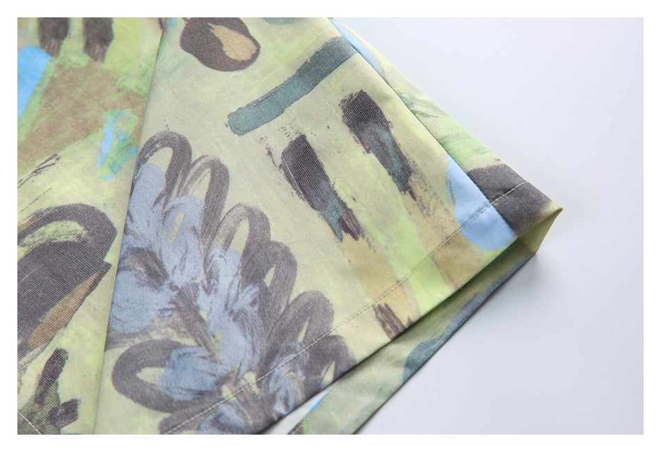 Close-up of a stitched sleeve edge on a shirt with a lime, blue, and charcoal abstract floral print.