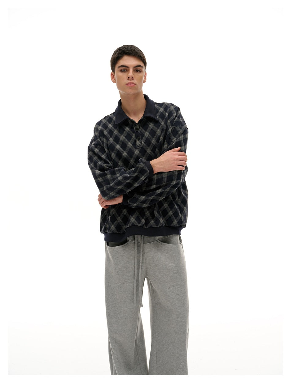 Closer view of a model wearing a navy and gray diamond-plaid pullover with dark collar, cuffs, and hem.