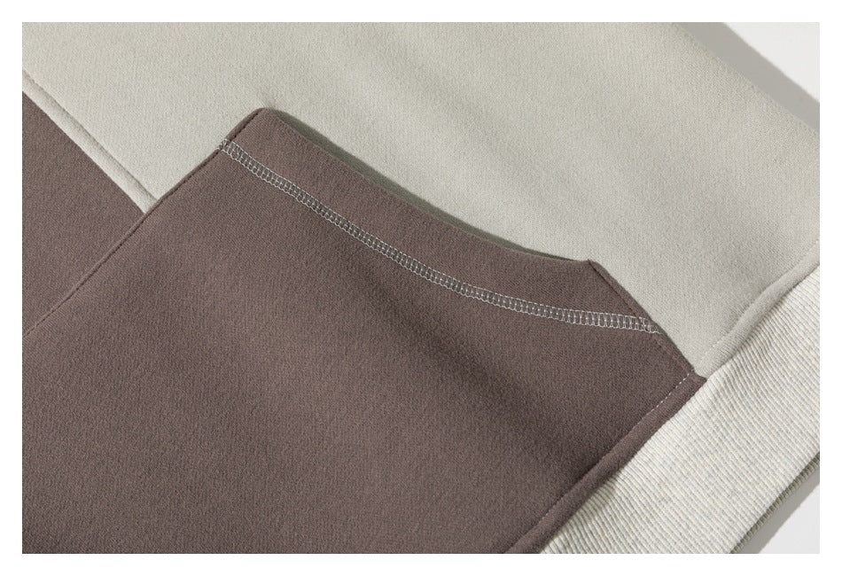 Close-up of the sweatshirt's taupe panel, cream ribbed edge, and visible overlock stitching.